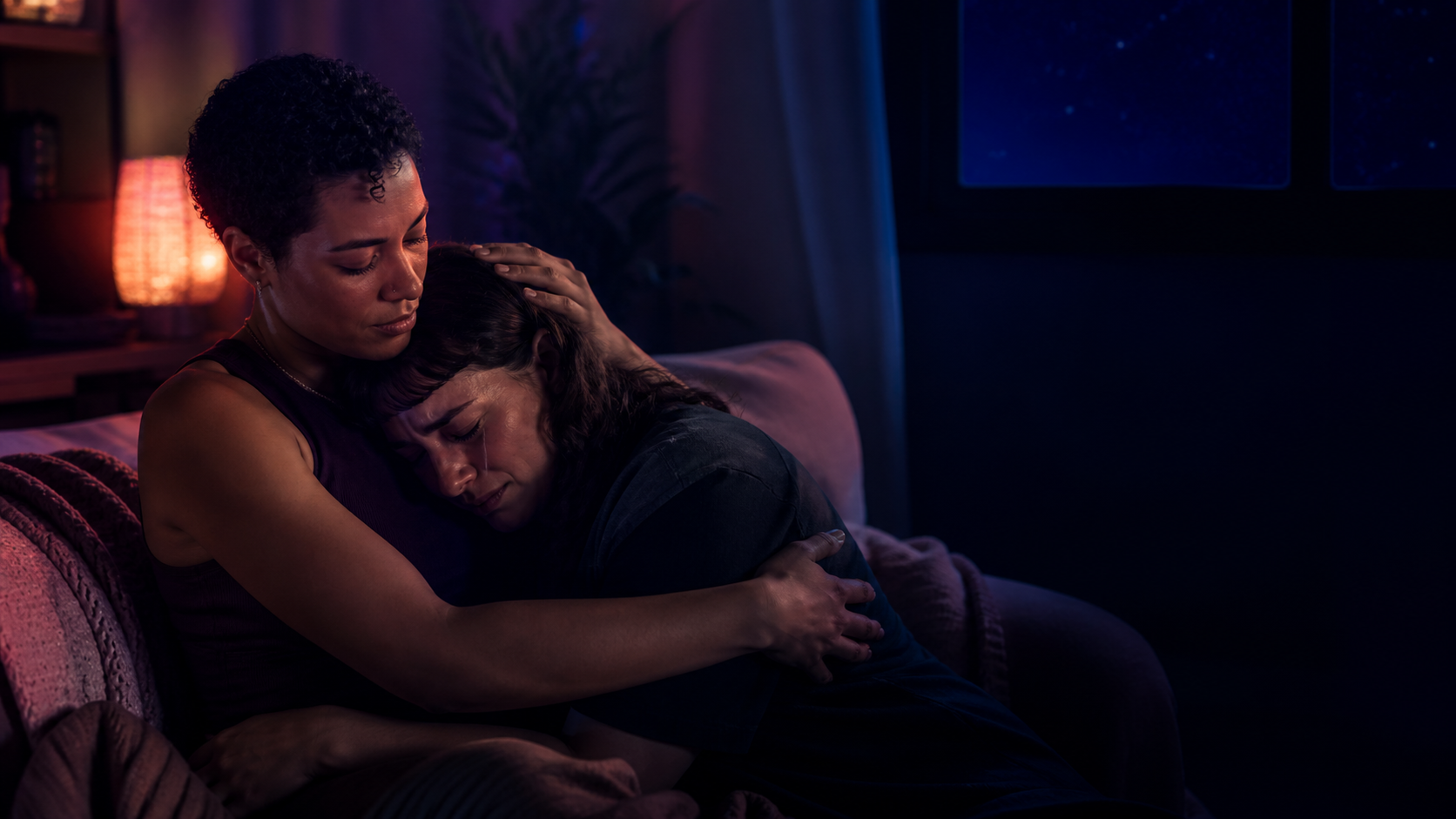 One adult gently holding and comforting another adult who is crying